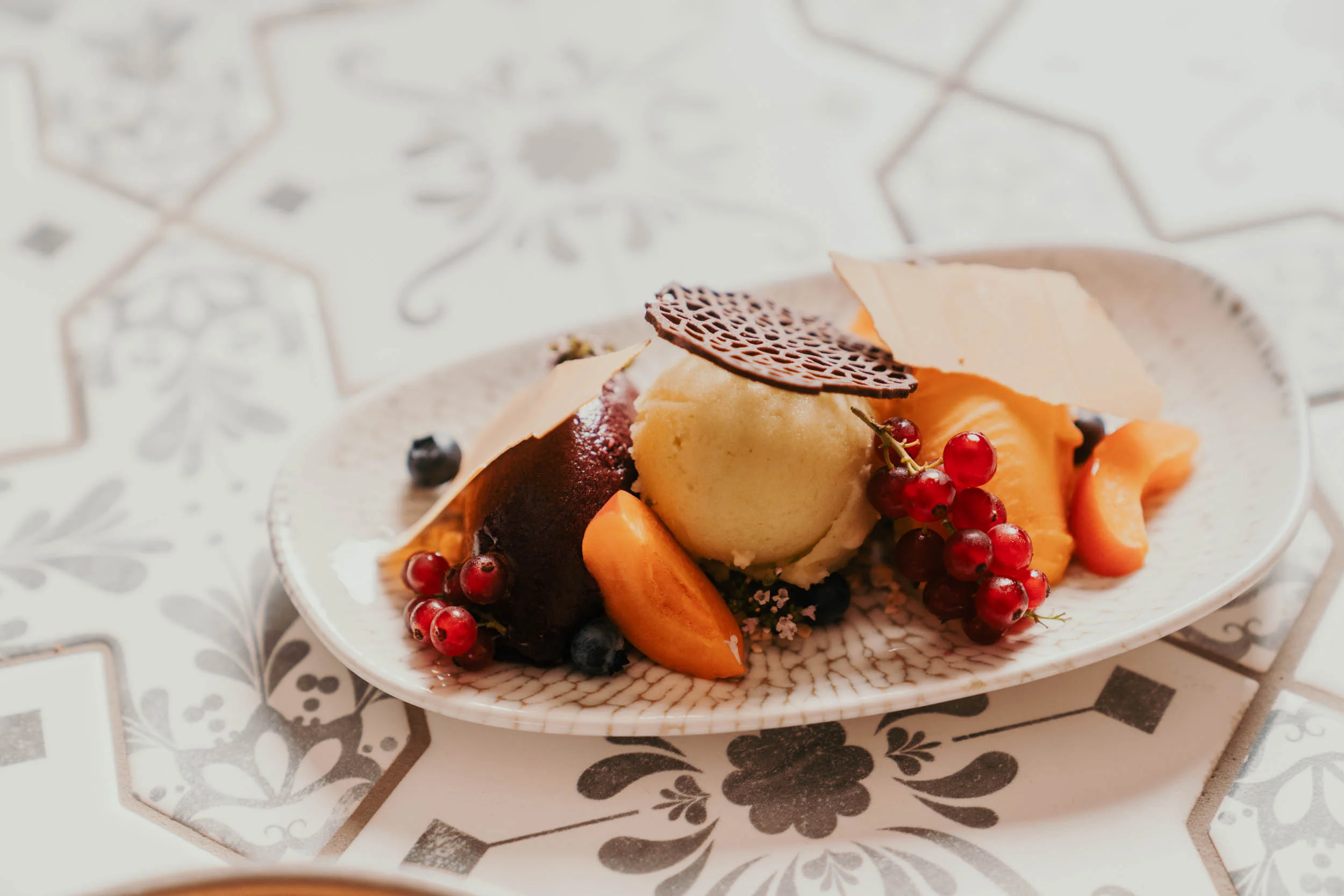 Feines Dessert mit einem Marillenknödel und Obst verziert