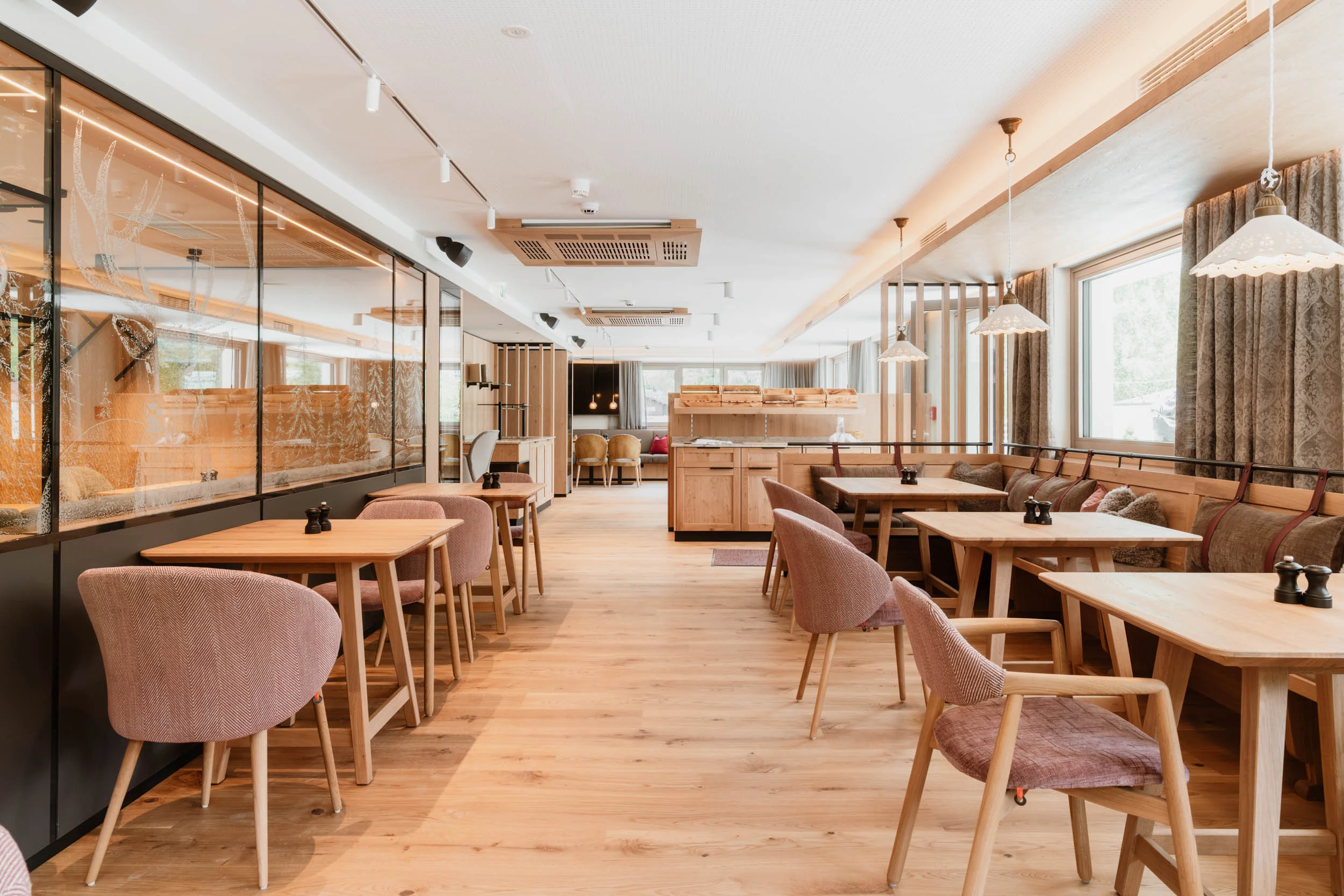 Restaurantbereich mit Holzboden und einem Gang. Links und Rechts sind kleine Tische