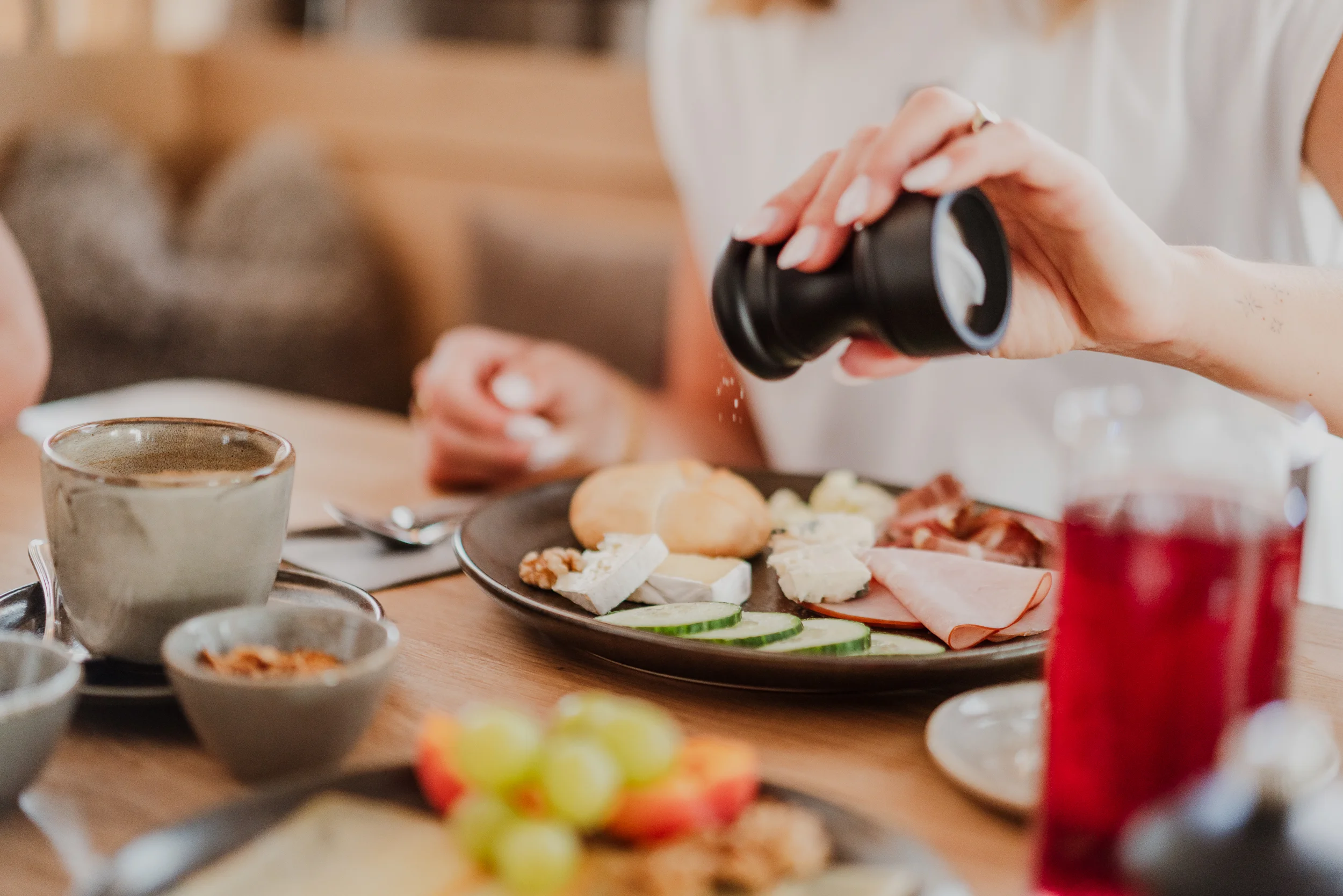Reich gedeckter Frühstückstisch mit Käse- und Wurstplatte sowie einem Getränk und Kaffee.