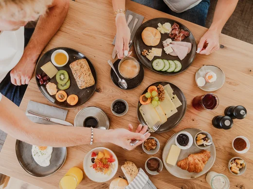 Warum wir Ziach & Candy, deine Unterkunft in Großarl, sind. Frühstückstisch mit einer Auswahl an Semmeln, Marmelade, Eiern & Käse