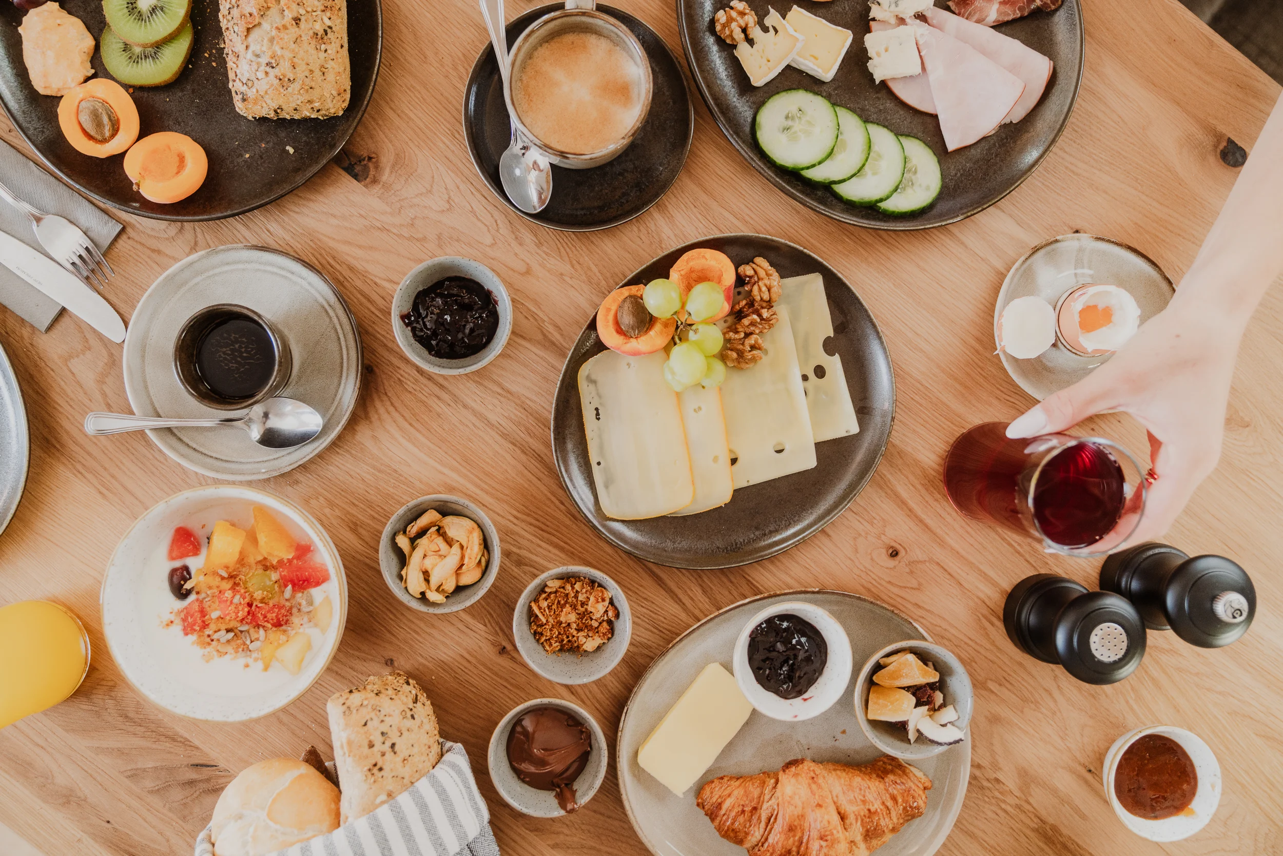 Reich gedeckter Frühstückstisch mit Käse, Croissant, Kaffee und Obstsalat